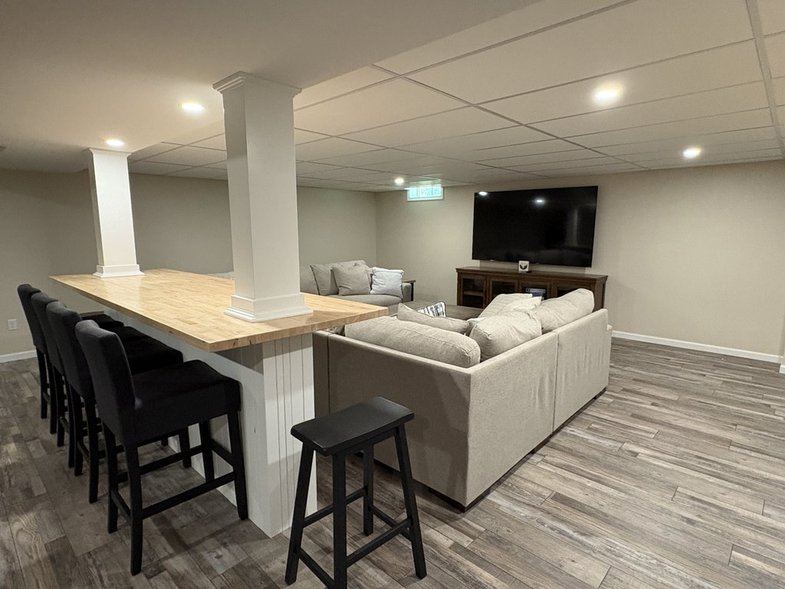 Lower-level bar with stools and TV