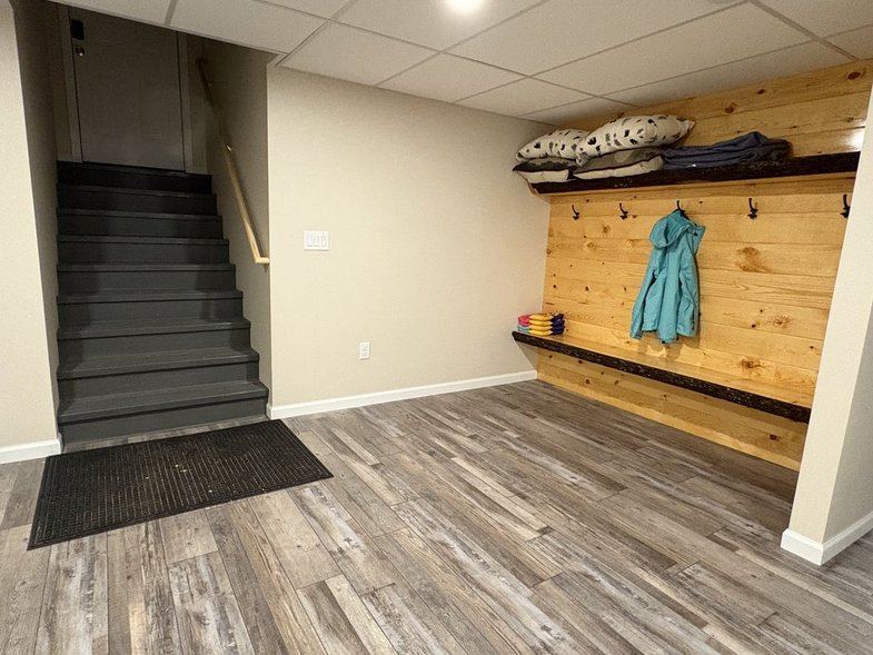 Lower-level entry with wood coat wall, bench and stairs